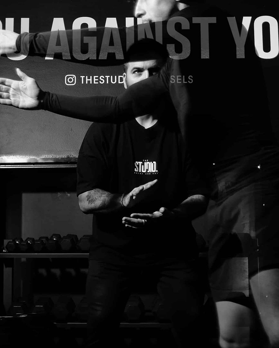 Un coach de The Studio encourage un membre devant le mur « You against you »